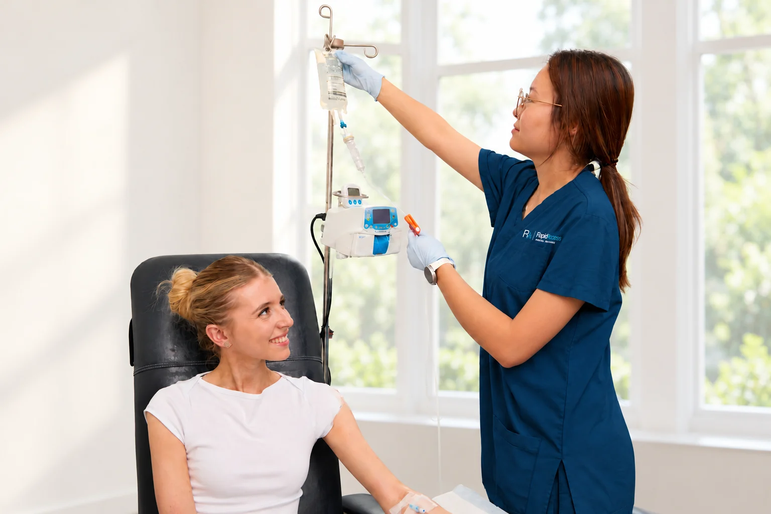 Nurse preparing an infusion beside a patient at our clinic